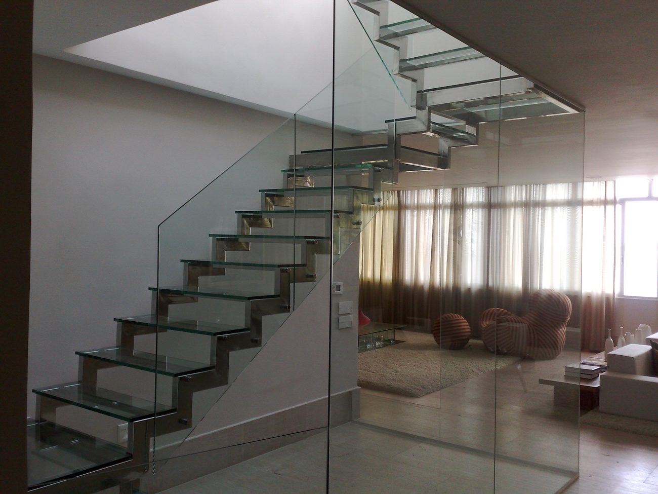Escada com degraus de vidro e estrutura em aço inox